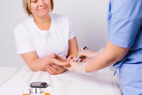 Diabetessköterska kollar blodsockret på patient med Diabetes typ 2.